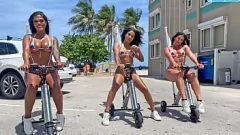 Redare Latina Camgirls în bikini se plimbă cu triciclete electrice pe plaja publică
