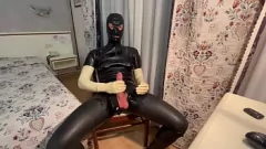 Reproduzir Gata peituda em macacão de látex é amamentada por um garanhão de pau grande usando luvas brancas de látex